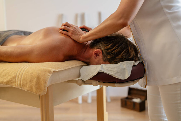 Masajista femenina aplicando presión con las manos en la espalda del cliente masculino. Wellness Hotel Concept image - Foto, Imagen