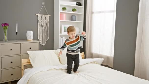 Egy vidám kisgyerek az ágyon játszik egy otthonos hálószobában, gondtalan gyerekkori pillanatokat ábrázolva a házban.. - Felvétel, videó