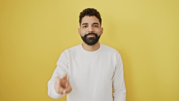Smiling young man winking, standing victorious, throwing a two-fingered v sign on an isolated yellow background - Footage, Video