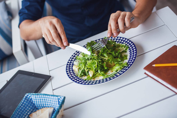 Обрезанное изображение молодого человека, поедающего салат в кафе - Фото, изображение
