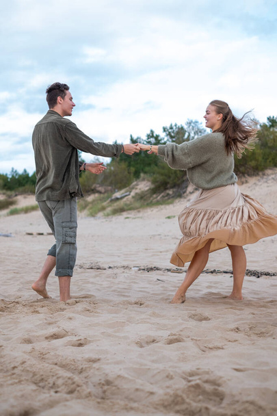 Energetisches Paar, das am Strand tanzt, mit dynamischer Bewegung und fröhlichem Ausdruck. Perfekt für Themen wie aktiven Lebensstil und Glück. Hochwertiges Foto - Foto, Bild