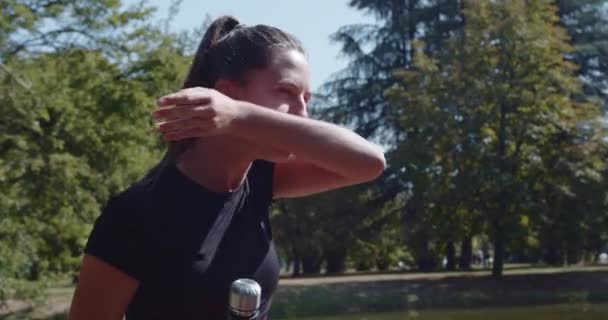 Žena sportovec s přestávkou pít vodu ze sportovní láhve při tréninku v parku za slunečného dne, předvádění zdraví a fitness. - Záběry, video