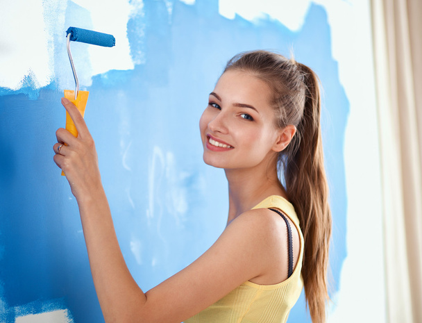 Feliz hermosa joven mujer haciendo pintura de pared, - Foto, Imagen