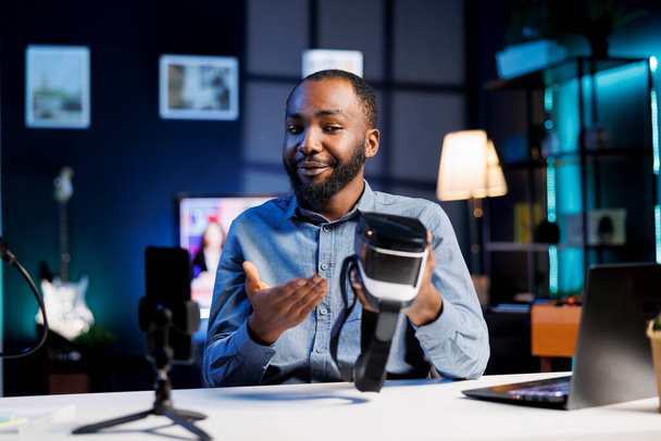 Tech content creator filmen technologie review van onlangs gelanceerde futuristische VR bril, proberen en geven zijn indrukken aan het publiek. Internet ster indringende virtual reality apparaat - Foto, afbeelding