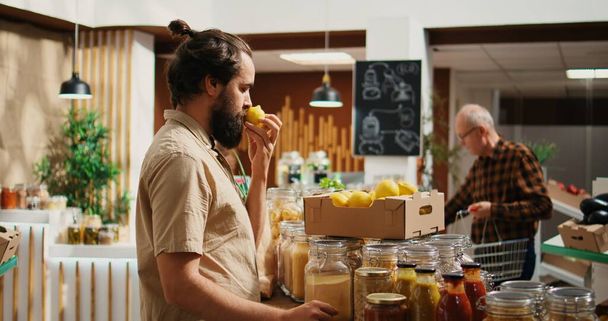 Homem em zero loja de resíduos de compras de frutas, sentindo pressa dopamina enquanto cheira-los. Cliente que experimenta felicidade nostálgica enquanto se sente agradável aroma limões na loja local, zoom out shot - Foto, Imagem