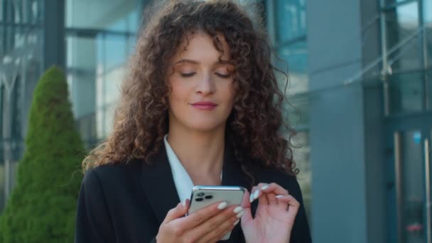 Кавказька бізнес-леді молода дівчина використовує смартфон в місті думає ідея мрія жінка-роботодавець офіс менеджер перегляд мобільного телефону інтернет-дані бізнес-мережа онлайн покупки на відкритому повітрі - Кадри, відео