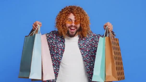 ショッピングバッグ,広告割引,笑顔を示すハッピーコーカサス人男性は,低価格で驚きました, ブラックフライデーの休日にショッピング. 青い背景で孤立したスタイリッシュな若者. コピースペース - 映像、動画