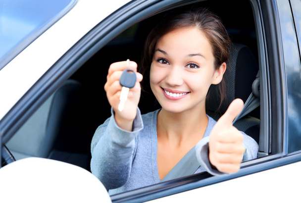 Chica feliz en un coche mostrando una llave y el pulgar hacia arriba gesto
 - Foto, Imagen