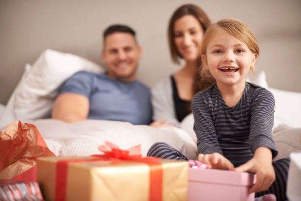 Πορτρέτο, υπνοδωμάτιο και κορίτσι με γονείς, δώρο ή Χριστούγεννα με γιορτή ή συγκόλληση μαζί. Πρόσωπο, οικογένεια ή παιδί με μητέρα ή πατέρα με εορταστική περίοδο ή παρόν με ευτυχία, σπίτι ή χαμόγελο. - Φωτογραφία, εικόνα