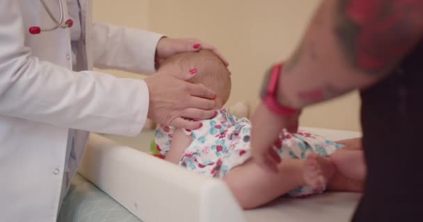 Vrouwelijke kinderarts die pasgeboren baby 's onderzoekt in het ziekenhuis. Ze controleert de baby 's hoofd en gebruikt stethoscoop om de ademhaling te controleren. - Video