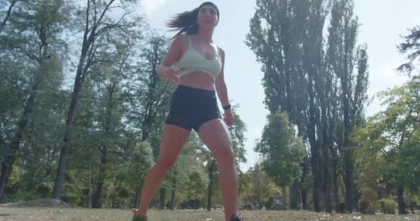 In het park, een sportmeisje en haar vriend hebben plezier gooien en vangen met een rugbybal, genieten van het buitenleven. - Video