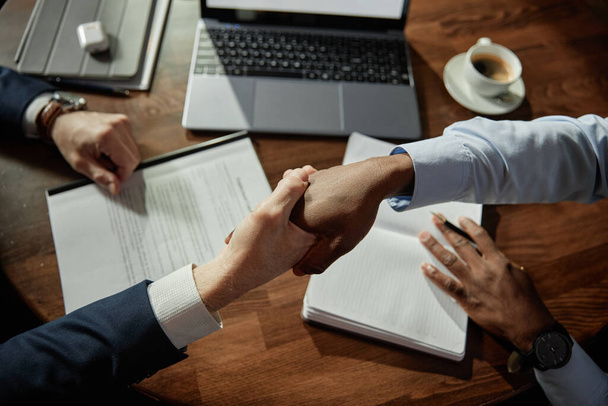 Visão de alto ângulo dos empresários apertando as mãos para concluir um acordo durante a reunião de negócios - Foto, Imagem