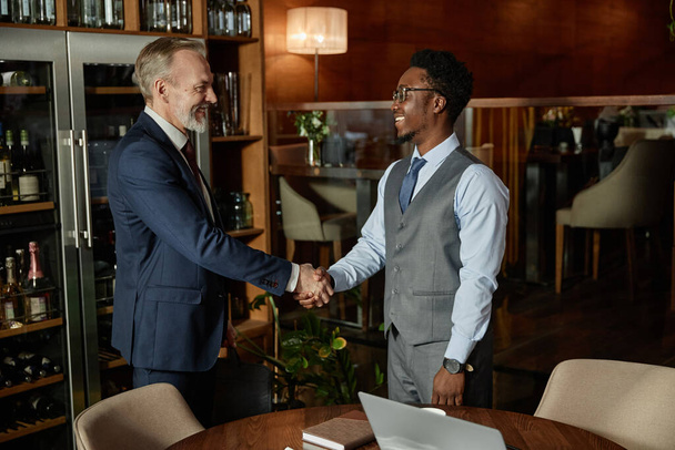 Socios de negocios estrechándose la mano y saludándose en la reunión en el restaurante - Foto, imagen