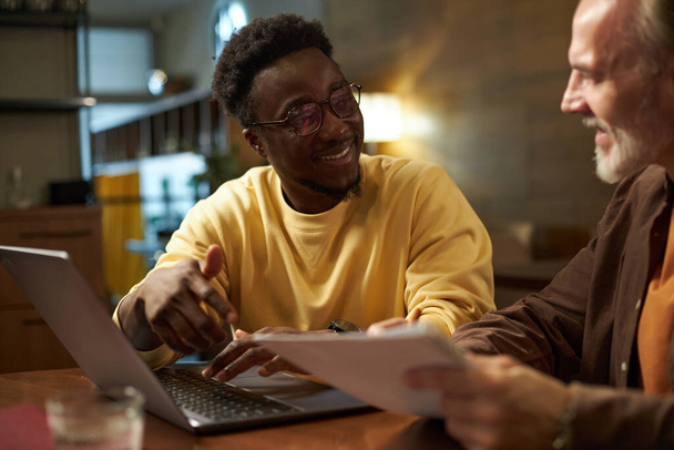 Афроамериканский бизнесмен разговаривает со своим коллегой во время обсуждения бизнес-плана за столом во время встречи в кафе - Фото, изображение