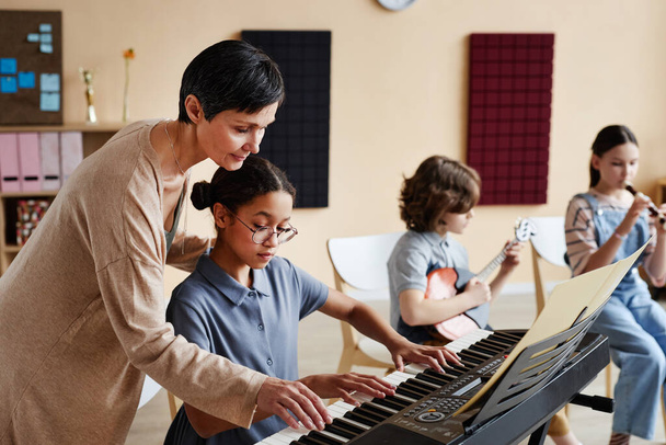 Professional teacher learning children to play musical instruments in music class - Photo, Image