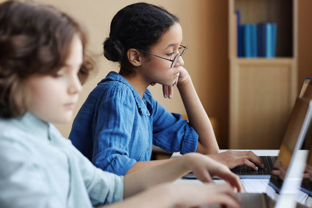情報技術レッスン中にテーブルに座っている間,コンピュータの仕事に集中する学校の子供たち - 写真・画像