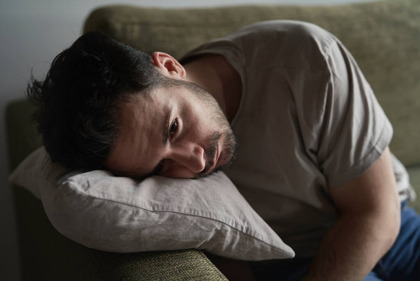 Close up of thoughtful man with head on pillow - Photo, Image
