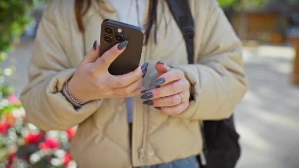 Jeune femme souriant en parlant sur un téléphone portable à l'extérieur dans un parc ensoleillé - Séquence, vidéo