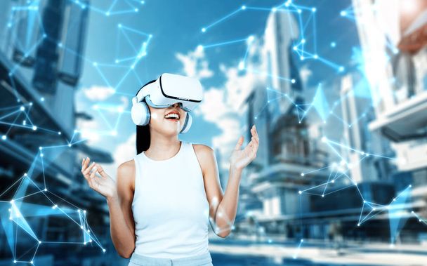 El soporte femenino lleva auriculares VR blancos y el blanco sin mangas conectan la metáfora, la tecnología futura crea una comunidad del ciberespacio. Ella mira a su alrededor y gesticular disfrutar de la construcción de la fantasía en meta. Alucinaciones. - Foto, imagen
