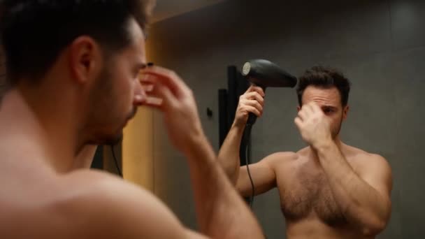 Καυκάσιος άνδρας στεγνώνει τα μαλλιά με στεγνωτήρα μαλλιών - Πλάνα, βίντεο