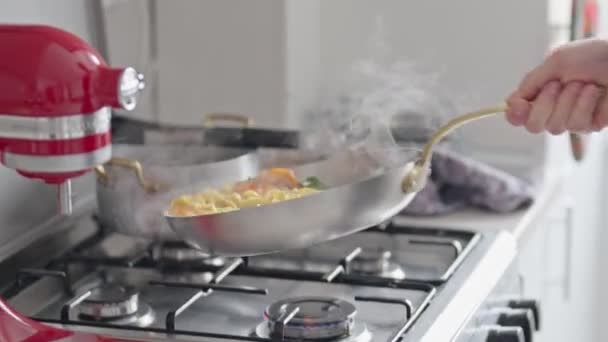 Pessoa lançando macarrão na panela no fogão, cena culinária dinâmica em casa. Concentre-se em comida caseira e um estilo de vida saudável. - Filmagem, Vídeo