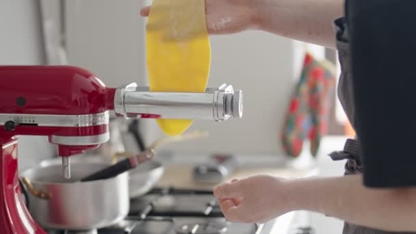 Ένα άτομο χρησιμοποιεί μια κόκκινη μηχανή κουζίνας για να ανοίξει φρέσκια, σπιτική ζύμη ζυμαρικών. Η διαδικασία αναδεικνύει μια εμπειρία μαγειρικής στο σπίτι, εστιάζοντας στη δημιουργία της ιταλικής κουζίνας με μια εγχώρια πινελιά. - Πλάνα, βίντεο