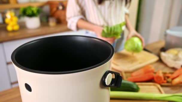 Young woman recycling vegetables peels in a compost bin. Housewife cooking food and composting organic waste in a bokashi container at home. Ecological and sustainability concept - Footage, Video