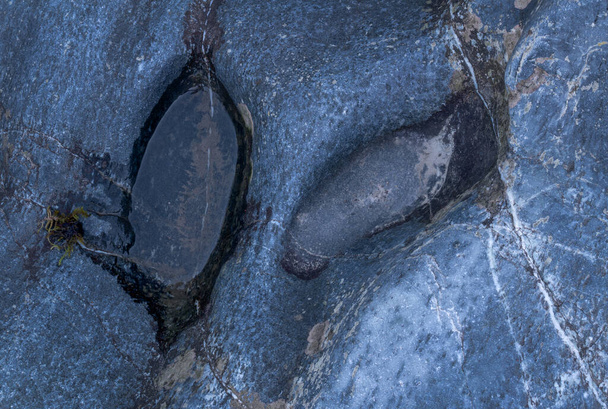 Kleine Pfütze in blauem Gestein in Nahaufnahme, Delle in Stein gefüllt mit Wasser zur blauen Stunde - Foto, Bild