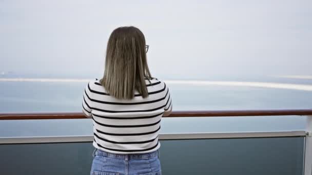 Eine Frau genießt den Meerblick vom Deck eines Kreuzfahrtschiffes und weckt damit ein Gefühl von Reisen und Freizeit. - Filmmaterial, Video