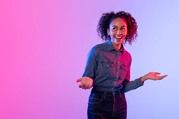 Welcoming woman with curly hair and open arms, colorful illuminated background - Photo, Image