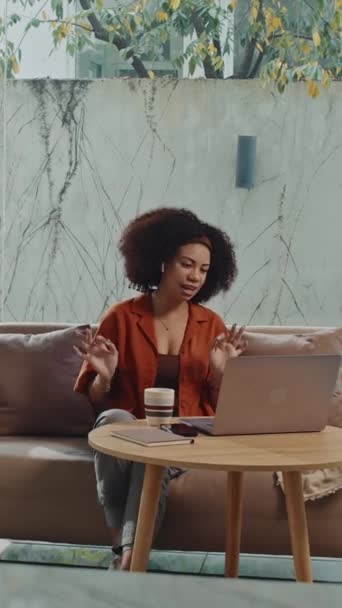 Colpo pieno verticale di dipendente freelance femminile che parla su video davanti a computer portatile in salotto - Filmati, video