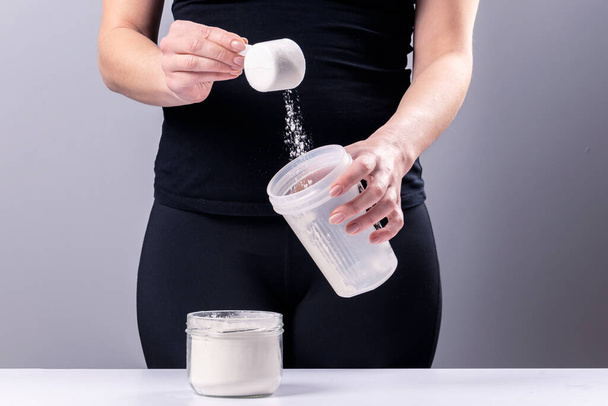 Woman makes a collagen mixture in a mixing glass. Sports nutrition: drink with protein - Photo, Image