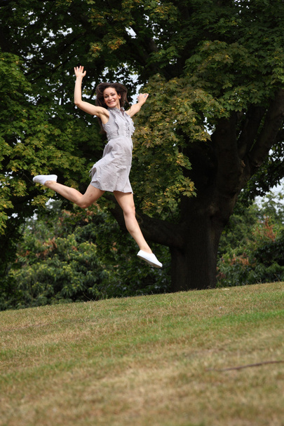 High flying jump for joy beautiful girl in park - Foto, afbeelding