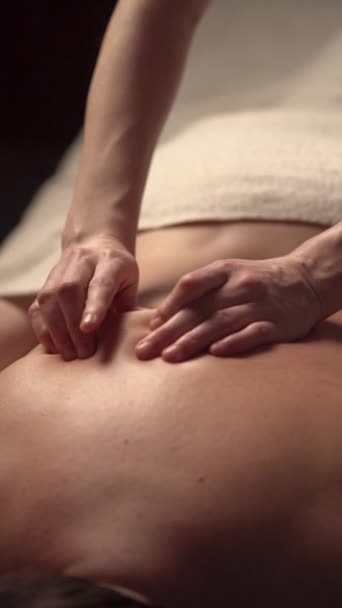 Masaje terapéutico en el cuello para mujeres maduras tumbadas en un sofá de masaje en el centro de spa. Vídeo vertical - Imágenes, Vídeo