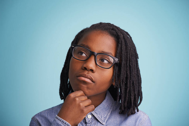 Thinking, glasses or black kid in studio with vision, solution or problem solving guess on blue background. Question, why or African teen model with emoji idea for brainstorming, memory or reflection. - Фото, изображение
