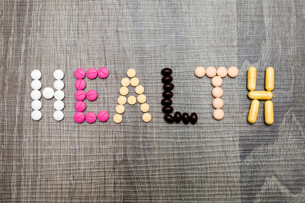 The word health written whith pills on a wooden background. - Foto, Bild