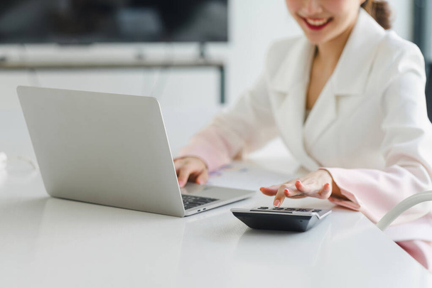 Fröhliche asiatische Geschäftsfrau arbeitet im Konferenzraum mit Laptop und Taschenrechner - Foto, Bild