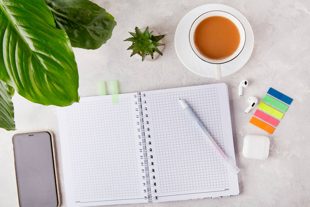 Schlank und einfach - Office Essentials Flachlagen mit Stift und Notizblock mit einer Tasse Kaffee, klebrigen Aufklebern, Kopfhörern. - Foto, Bild