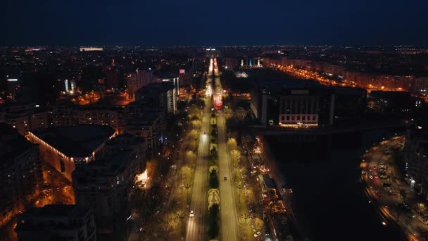 夜の照らされた街並みの空中ドローンビュー. ルーマニアのブカレストの道路を移動する - 映像、動画