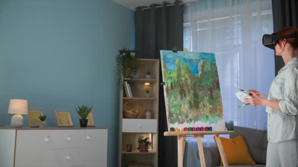 Augmented Reality: Moderne kreative Künstlerin zeichnet Bild mit Farben und Pinseln auf Leinwand, während sie in einem gemütlichen Raum steht - Filmmaterial, Video