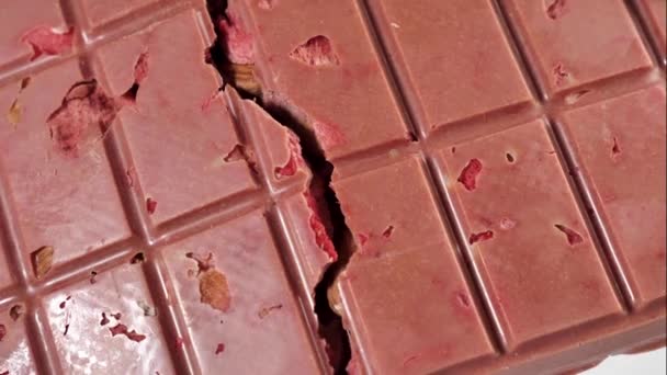 Una barra de ruptura de chocolate de rubí rosa con fresas liofilizadas y almendras de cerca,. Un postre saludable a base de bayas y frutos secos - Metraje, vídeo