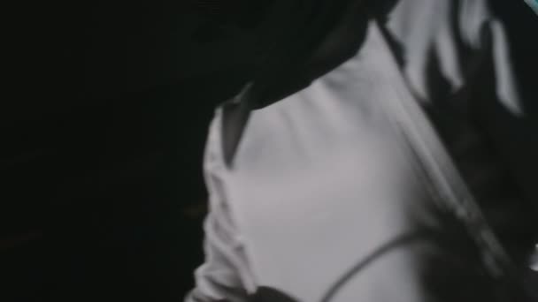 Πλάγια κομμένα πλάνα από fencer αλουμινόχαρτο σε λευκή επένδυση στολή που χτυπήθηκε από ξιφασκία ξιφασκίας κατά τη διάρκεια της εκπαίδευσης ή του ανταγωνισμού σε σκοτεινό δωμάτιο - Πλάνα, βίντεο