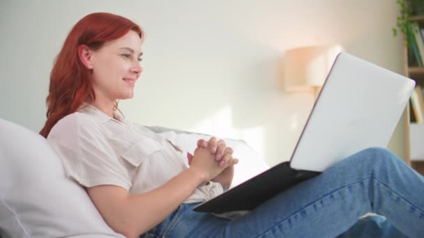όμορφη χαμογελαστή γυναίκα περιήγηση σελίδες στο διαδίκτυο ή σε ένα ηλεκτρονικό κατάστημα, ενώ βρίσκεται στο κρεβάτι στο δωμάτιο - Πλάνα, βίντεο