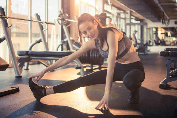 Fit sportovní žena protahování nohy před tréninkem v tělocvičně. - Fotografie, Obrázek