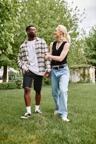 多文化カップル,幸せなアフリカ系アメリカ人男性,そして屋外の緑豊かな草の中に一緒に立っている白人女性.. - 写真・画像