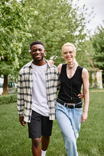 Onnellinen monikulttuurinen pari, afroamerikkalainen mies ja valkoihoinen nainen, jotka seisovat yhdessä puiston vehreässä nurmessa.. - Valokuva, kuva