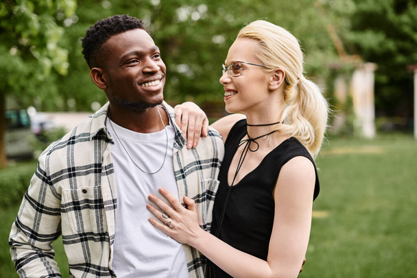 Una pareja multicultural, un hombre afroamericano y una mujer caucásica se unen en un parque, compartiendo un momento de felicidad. - Foto, Imagen