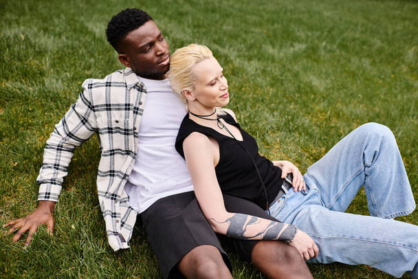 Una coppia multiculturale, un uomo afroamericano e una donna caucasica, distesi contenti sull'erba in un parco. - Foto, immagini
