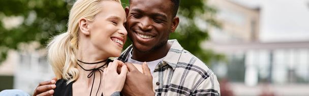 Un couple multiculturel heureux, un homme afro-américain et une femme blanche, debout ensemble dans un parc. - Photo, image