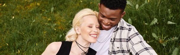 Een gelukkig multicultureel koppel, een Afro-Amerikaanse man en een blanke vrouw, die buiten in een park naast elkaar staan. - Foto, afbeelding